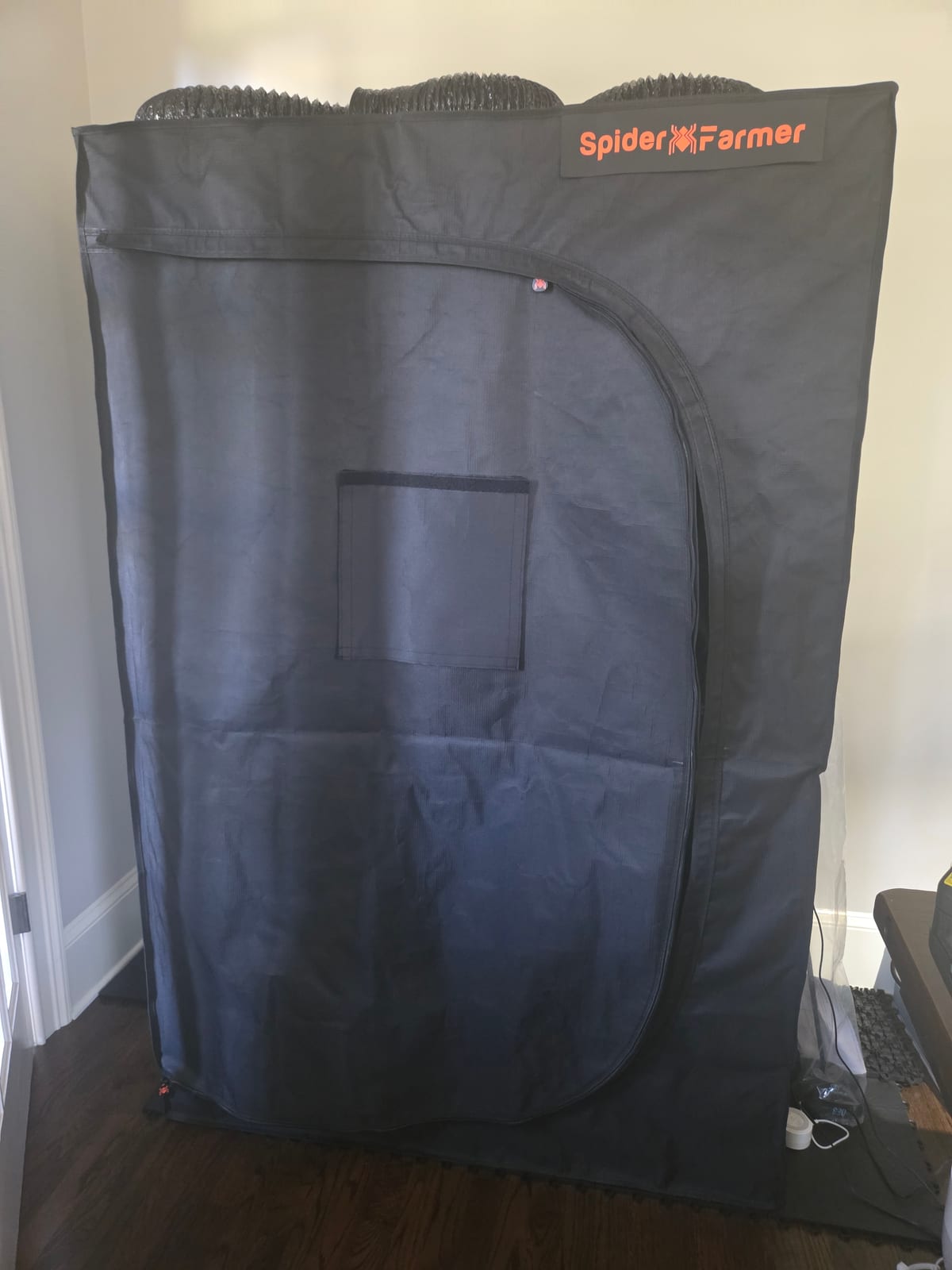Black Spider Farmer grow tent, zipped closed, standing in the grow room